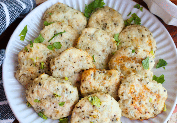 Homemade chicken breakfast sausage patties on a white plate, garnished with fresh parsley. Juicy, golden-brown, and perfectly seasoned, these protein-packed chicken sausages make a healthy, flavorful breakfast option made with Springer Mountain Farms Simply Superior Chicken™.