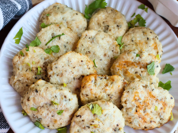 Homemade chicken breakfast sausage patties on a white plate, garnished with fresh parsley. Juicy, golden-brown, and perfectly seasoned, these protein-packed chicken sausages make a healthy, flavorful breakfast option made with Springer Mountain Farms Simply Superior Chicken™.