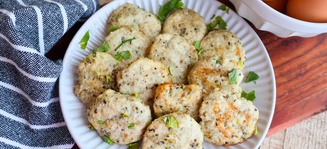 Homemade chicken breakfast sausage patties on a white plate, garnished with fresh parsley. Juicy, golden-brown, and perfectly seasoned, these protein-packed chicken sausages make a healthy, flavorful breakfast option made with Springer Mountain Farms Simply Superior Chicken™.