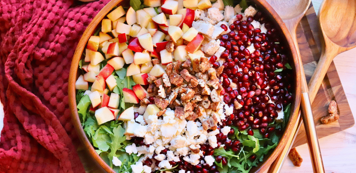 Healthy fall salad with Springer Mountain Farms Herb Poached Chicken, fresh apples, pomegranate seeds, candied pecans, and feta over arugula — easy seasonal recipe.
