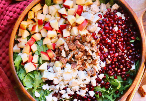Healthy fall salad with Springer Mountain Farms Herb Poached Chicken, fresh apples, pomegranate seeds, candied pecans, and feta over arugula — easy seasonal recipe.