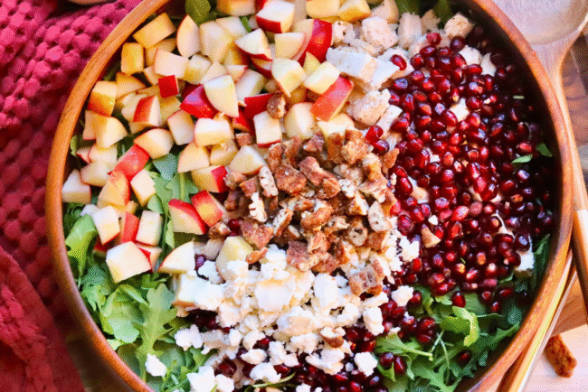 Healthy fall salad with Springer Mountain Farms Herb Poached Chicken, fresh apples, pomegranate seeds, candied pecans, and feta over arugula — easy seasonal recipe.