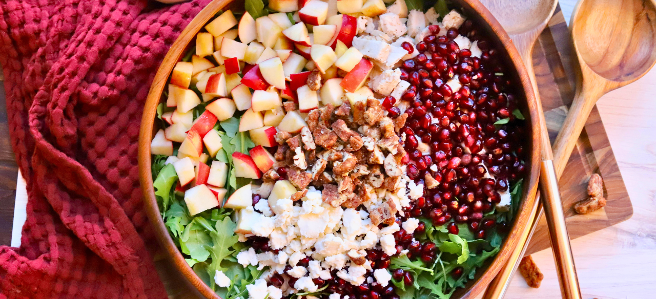 Healthy fall salad with Springer Mountain Farms Herb Poached Chicken, fresh apples, pomegranate seeds, candied pecans, and feta over arugula — easy seasonal recipe.