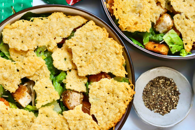 Crispy chicken Caesar salad topped with crunchy parmesan crisps and golden potatoes, served with fresh romaine and cracked black pepper.