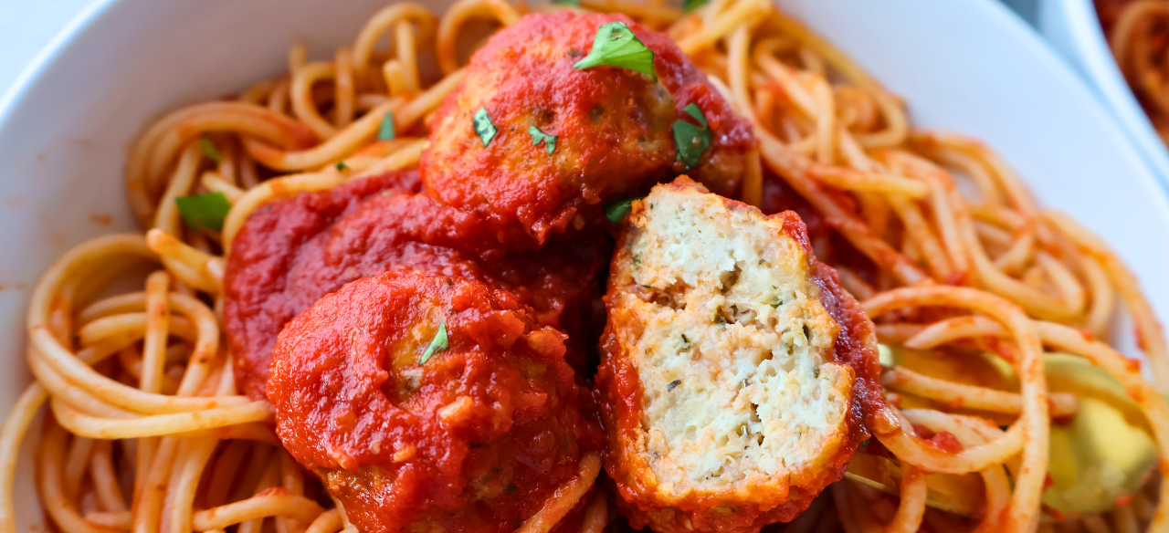 Close-up of spaghetti topped with juicy Italian chicken meatballs in marinara sauce, garnished with fresh parsley – perfect freezer-friendly dinner idea.