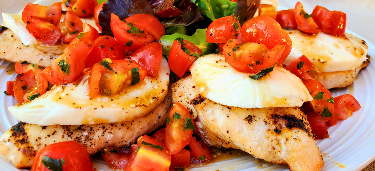 Grilled Springer Mountain Farms 4 oz boneless skinless chicken breasts topped with fresh mozzarella, cherry tomatoes, basil, and balsamic glaze for a healthy Caprese chicken recipe perfect for summer grilling.
