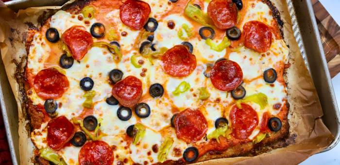 Protein-packed pizza made with a ground chicken crust, topped with melted cheese, pepperoni, olives, and peppers.