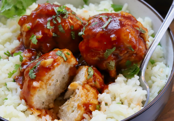 Sweet and sour chicken meatballs glazed in sticky sauce, served over white rice and garnished with fresh cilantro.