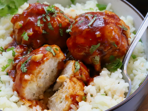 Sweet and sour chicken meatballs glazed in sticky sauce, served over white rice and garnished with fresh cilantro.
