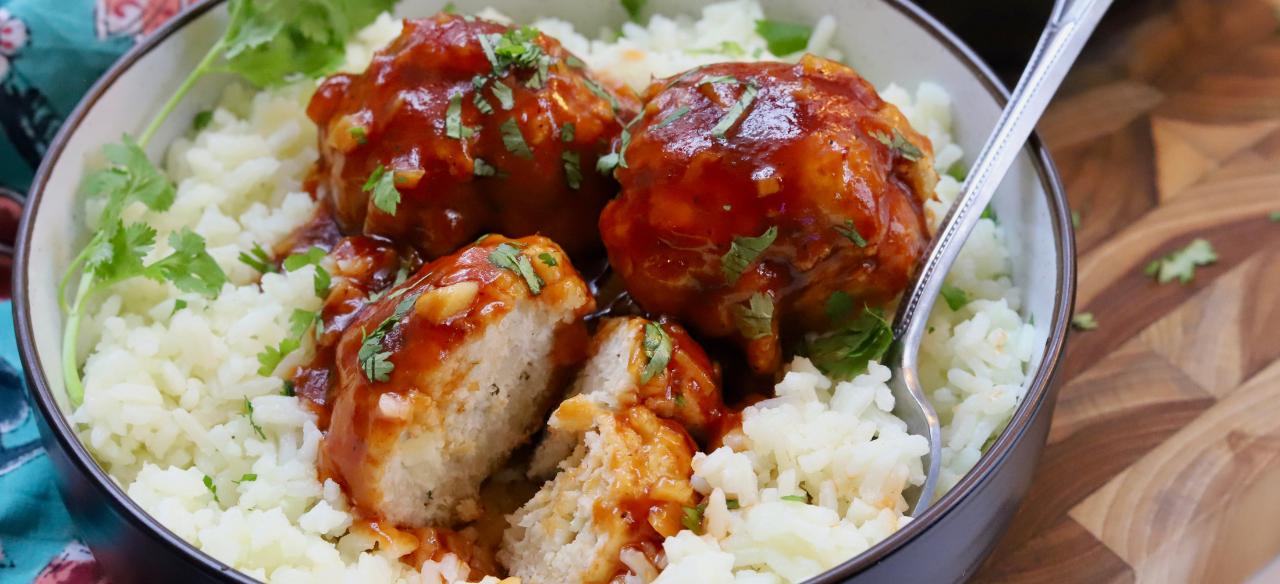 Sweet and sour chicken meatballs glazed in sticky sauce, served over white rice and garnished with fresh cilantro.