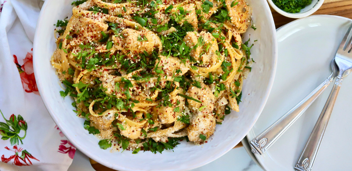 Korean Chicken Fettuccini Noodles topped with sesame seeds, cilantro, red pepper flakes, and green onions in a white bowl – spicy creamy Asian fusion pasta with chicken breast.