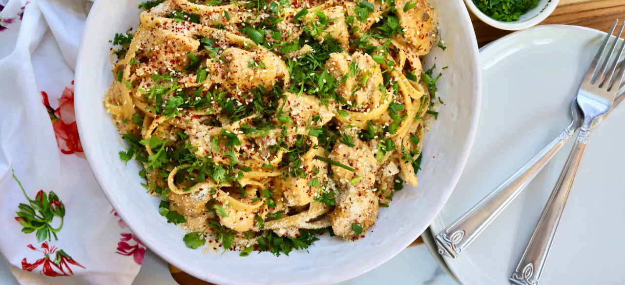 Korean Chicken Fettuccini Noodles topped with sesame seeds, cilantro, red pepper flakes, and green onions in a white bowl – spicy creamy Asian fusion pasta with chicken breast.