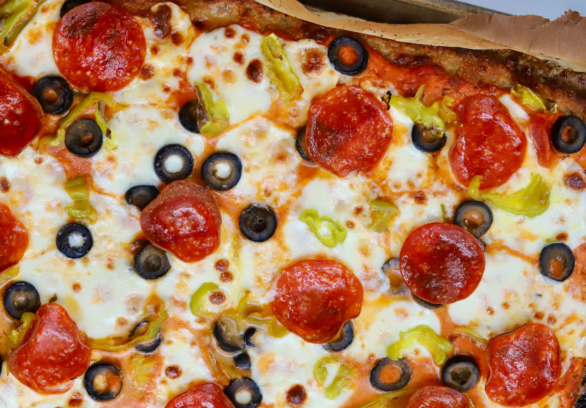 High-protein pizza made with a ground chicken crust, topped with melted mozzarella, pepperoni, black olives, banana peppers, and marinara sauce.