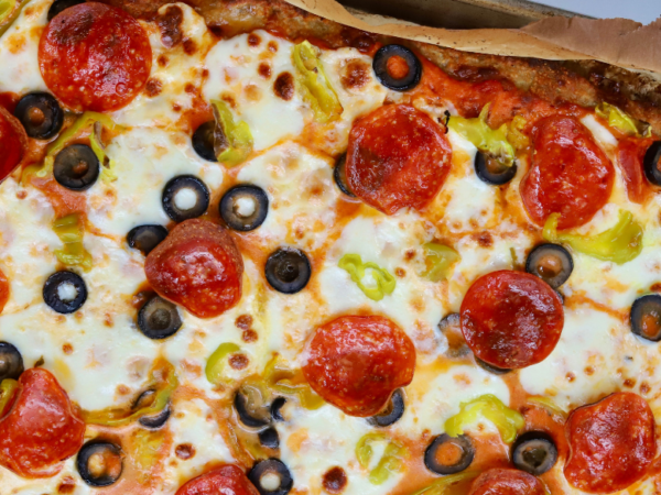 High-protein pizza made with a ground chicken crust, topped with melted mozzarella, pepperoni, black olives, banana peppers, and marinara sauce.
