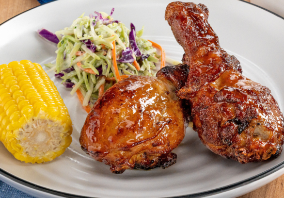 Air fryer chicken drumsticks glazed with peach BBQ sauce served with coleslaw and corn on the cob