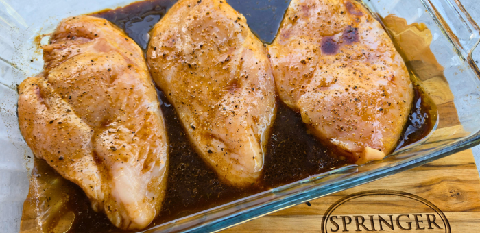 Chicken breasts marinating in seasoned marinade before grilling