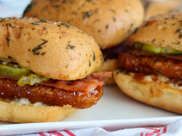 Hot honey chicken sliders with bacon, pickles and ranch made with Springer Mountain Farms fully cooked gluten free breaded chicken strip fritters.