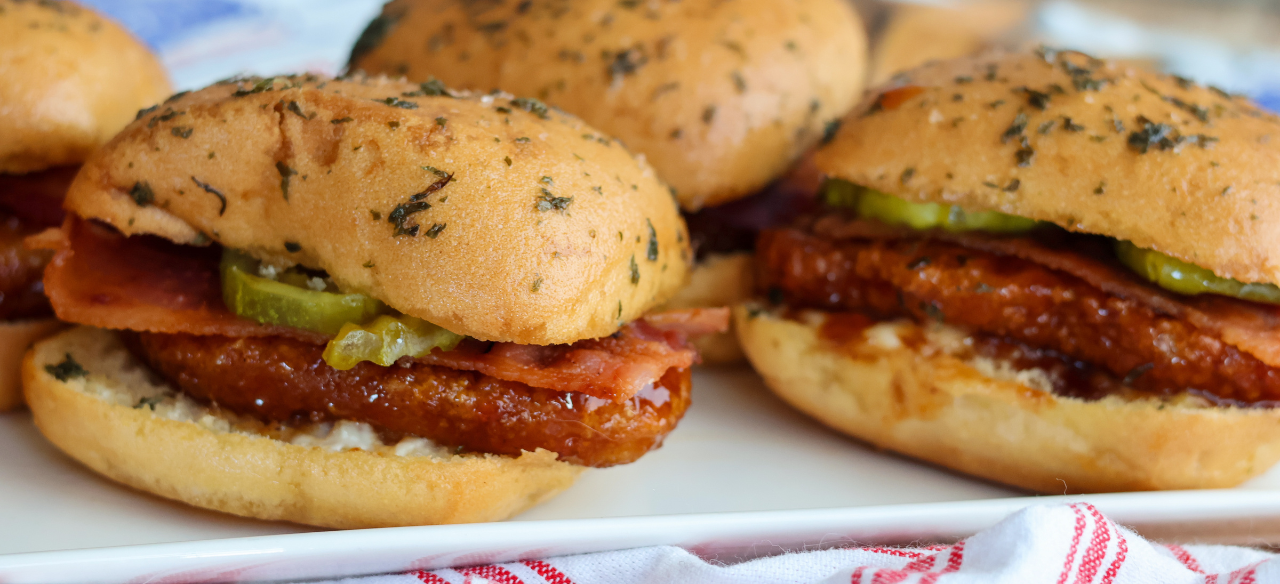 Hot honey chicken sliders with bacon, pickles and ranch made with Springer Mountain Farms fully cooked gluten free breaded chicken strip fritters.